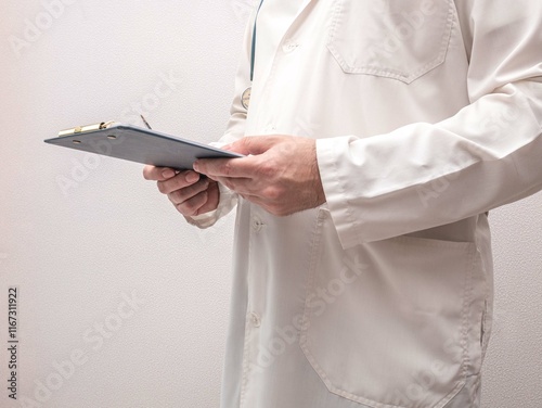 The male doctor holds a tablet for writing and a ballpoint pen. Writes recommendations, doctor's work. A place to copy photo