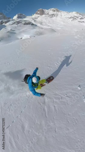 SELFIE: Clouds of fresh snow rise as man snowboards and turns on a snowy slope. Unrecognizable freerider is having an incredible ride on pristine steep mountain terrain after freshly fallen snow. photo