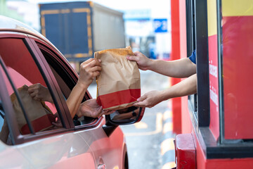 Hand Man in car receiving coffee in drive thru fast food restaurant. Staff serving takeaway order for driver in delivery window. Drive through and takeaway for buy fast food for protect covid19.
