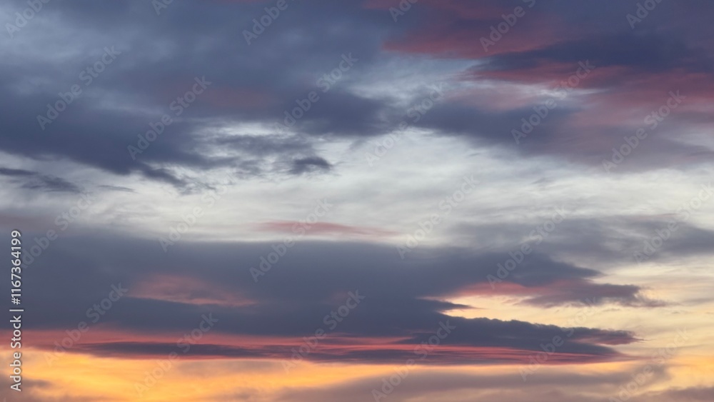 Obraz premium Light gray sky covered with thin clouds, soft sunset light colors them in a light purple-pink hue, creating a calm atmosphere.