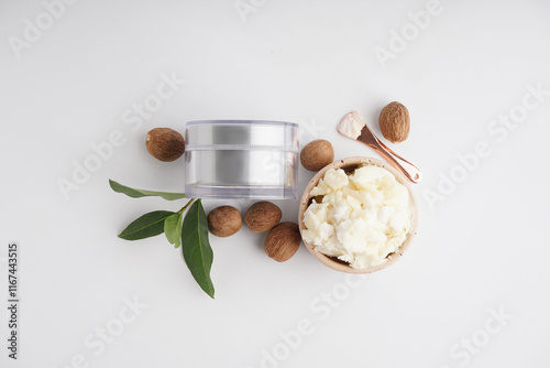 Composition with jar of cosmetic product, shea butter and nuts on light background