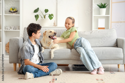 Happy sister and brother with cute Labrador dog sitting on sofa at home