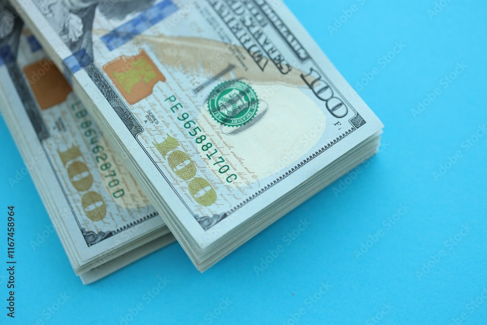 Big amount of hundred dollar bills in thick stack lies on bright blue color paper background Big amount of hundred dollar bills in thick stack lies on bright blue color paper background