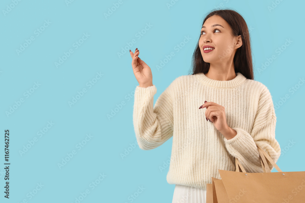 Pretty young woman with shopping bags pointing at something on blue background Pretty young woman with shopping bags pointing at something on blue background