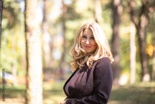 Portrait of a beautiful blonde young girl in a summer city park.
