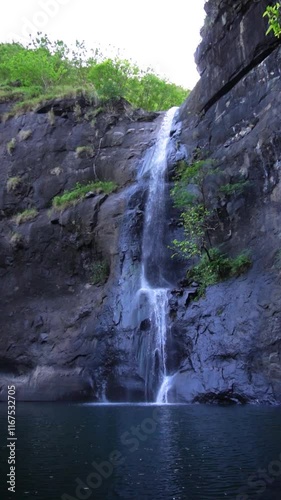 Slow Motion of Beautiful Natural Larangan Waterfall Flowing Down a Rocky Cliff Surrounded by Greenery in Sukabumi, Indonesia photo