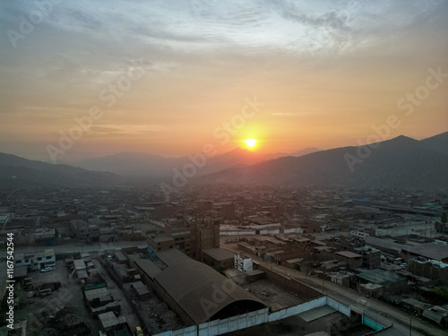 Foggy sunset over the city at the foot of the mountains