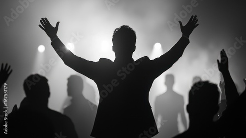 Silhouette of a person with arms raised in a crowd at a concert or event. photo