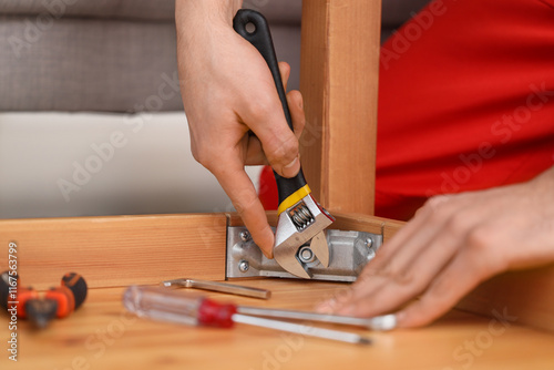 Obraz na plátně Male carpenter tightening chrome nut in wooden table with adjustable wrench, clo