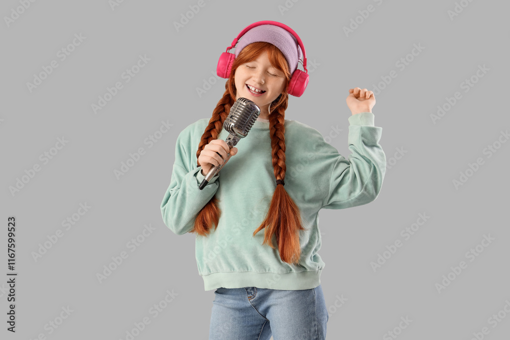 Teenage redhead girl in headphones with microphone singing on light background Teenage redhead girl in headphones with microphone singing on light background