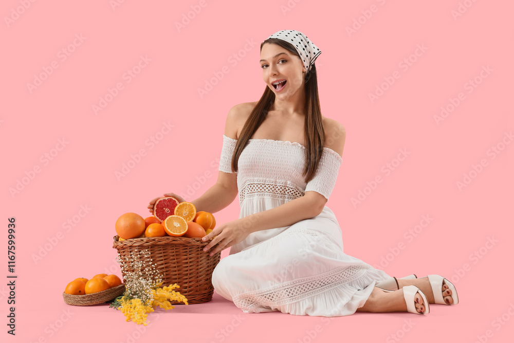 Young woman with basket of citruses sitting on pink background Young woman with basket of citruses sitting on pink background
