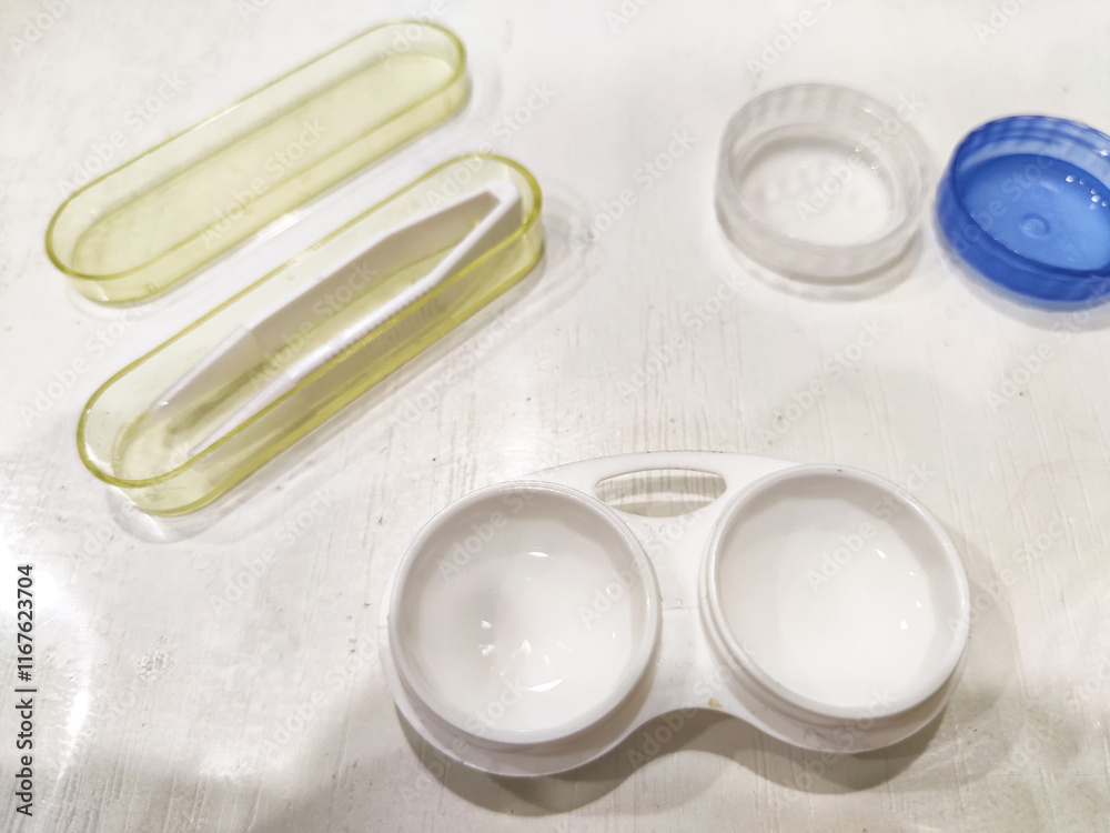 Assorted contact lenses cases and tools displayed on a flat surface in a bright room Assorted contact lenses cases and tools displayed on a flat surface in a bright room