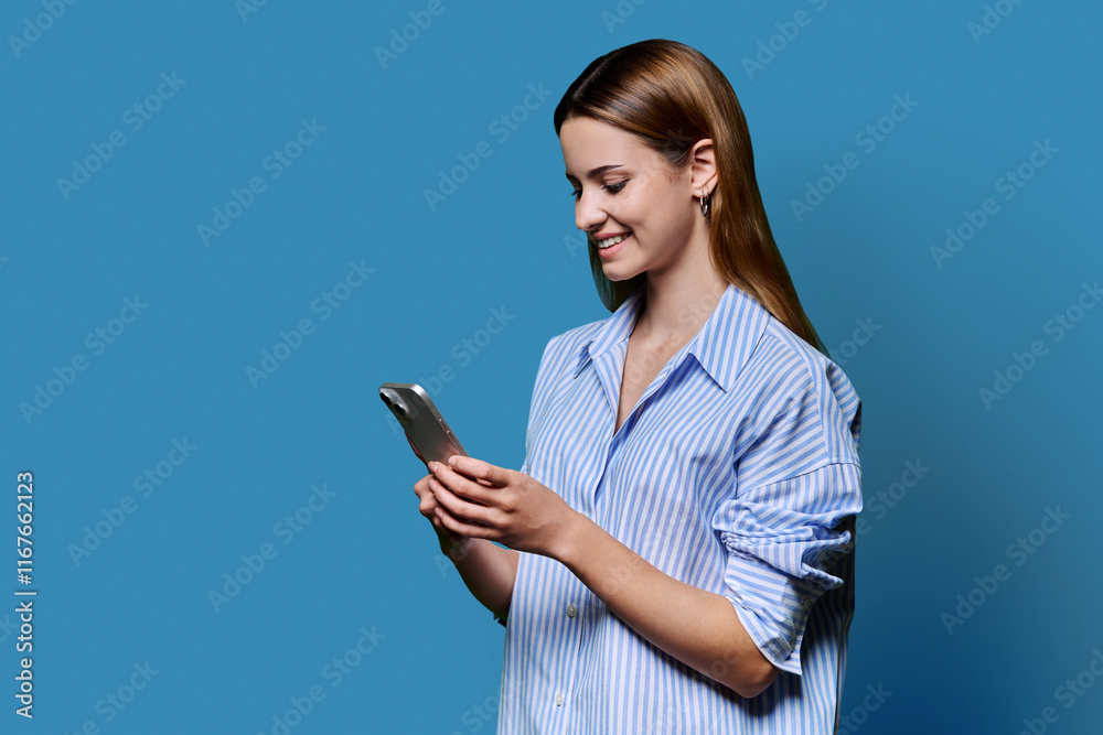 Young beautiful woman using smartphone on blue studio background Young beautiful woman using smartphone on blue studio background