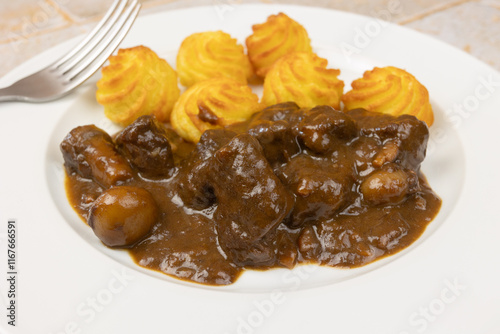 boeuf bourguignon et pommes de terre duchesse, en gros plan, dans une assiette photo