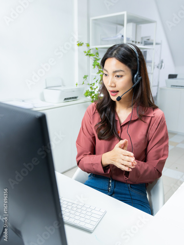 Friendly Asian woman working as a customer support operator with a headset in a call center office. Portrait of female sales agent talking to client working at desk. Customer service representative.