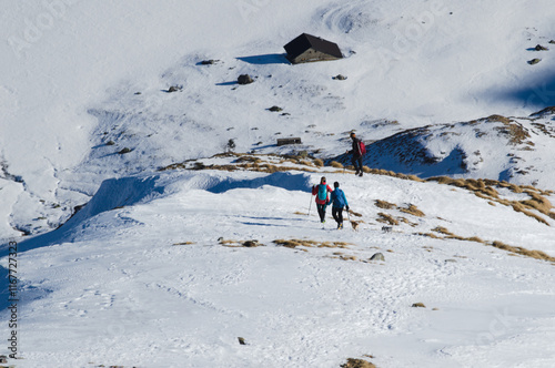 Hikers on the snowy slope of mount Madonnino, Orobie Alps, Italy.