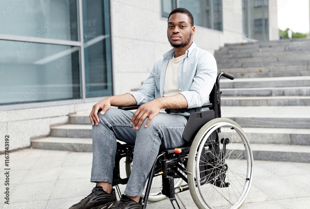 Accessible facilities for disabled people. Portrait of unhappy black impaired man in wheelchair next to siatrs without ramp, feeling stressed, having difficulty in entering building, free space Accessible facilities for disabled people. Portrait of unhappy black impaired man in wheelchair next to siatrs without ramp, feeling stressed, having difficulty in entering building, free space
