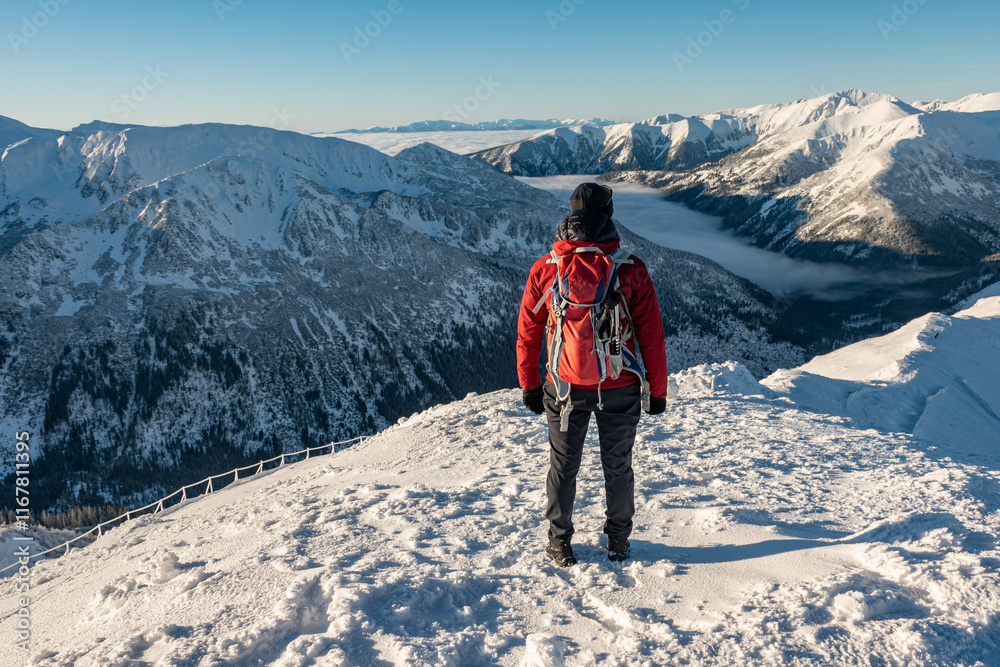 The climb of a determined professional and successful mountaineer in high-slope mountains. Tall man on rocky cliff watching down to landscape The climb of a determined professional and successful mountaineer in high-slope mountains. Tall man on rocky cliff watching down to landscape