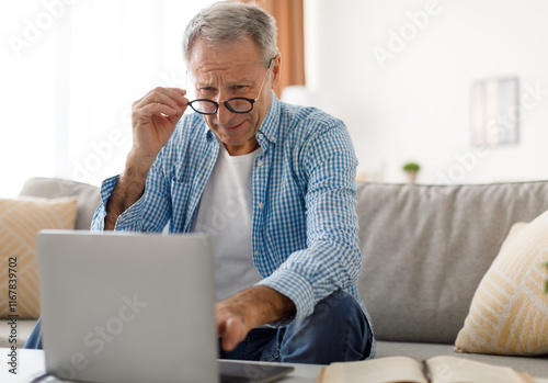 Poor Eyesight. Senior Man Squinting Eyes Using Laptop Wearing Eyeglasses Having Problems With Vision Sitting On Couch. Ophtalmic Issue, Bad Sight In Older Age, Macular Degeneration Concept photo