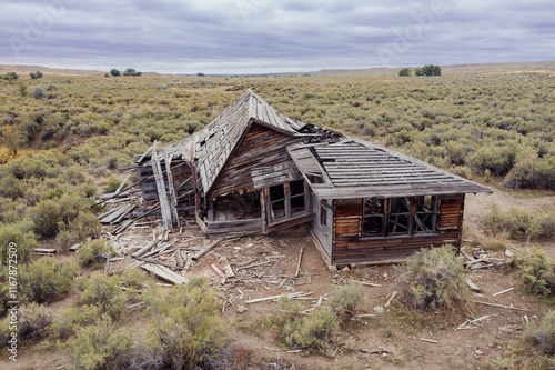 Abandoned wooden house in a desert landscape. Ruined structure surrounded by dry brush. A testament to time and nature's reclaiming. , Worland, Wyoming, USA. photo