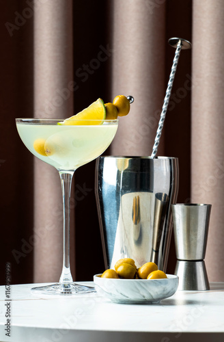 Mexican martini, alcoholic cocktail drink with tequila, liqueur, lime juice and green olives. Marble table with fabric curtain background photo