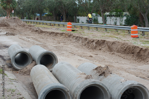 Wallpaper Mural Wide view over large concrete culvert pipe. At a large construction site Water Repair. Yellow bike rider on trail and fencing. Orange cones and barrel with leading lines.
 Torontodigital.ca
