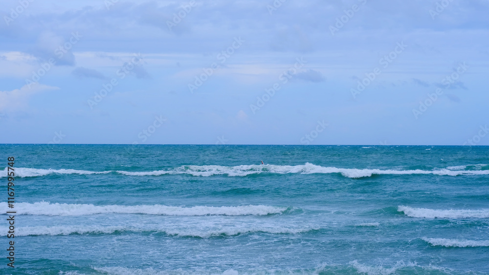 Ocean waves under a cloudy blue sky with blue sea water texture and color variations. Natural background texture. Ocean waves under a cloudy blue sky with blue sea water texture and color variations. Natural background texture.