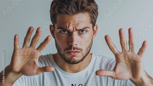 A stern-faced man firmly says “NO” while emphasizing rejection with strong hand gestures. His serious facial expression and assertive body language convey determination and refusal. photo