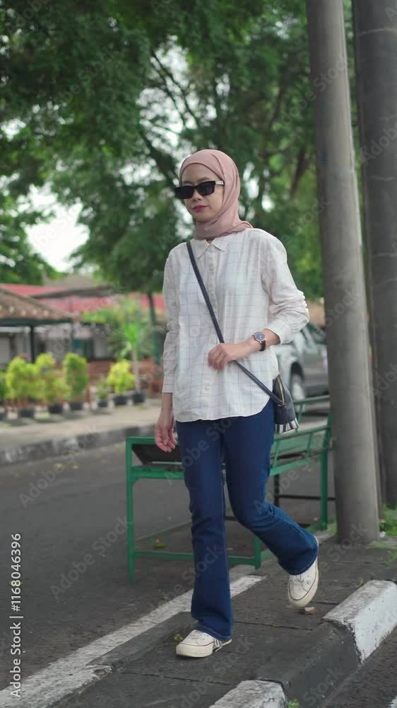 asian muslim woman wearing black sunglasses walking on the street asian muslim woman wearing black sunglasses walking on the street