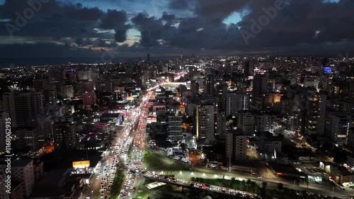 Wallpaper Mural Spectacular aerial footage of Santo Domingo at night, showcasing vibrant city lights, bustling traffic, towering buildings, and drifting clouds over the skyline in a dynamic urban panorama. Torontodigital.ca