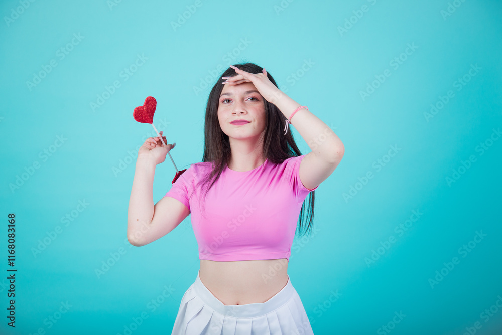 Horizontal Photo of cupid girl for valentines day wearing a pink top and white skirt, posing against a turquoise background to celebrate Valentine's Day. Horizontal Photo of cupid girl for valentines day wearing a pink top and white skirt, posing against a turquoise background to celebrate Valentine's Day.