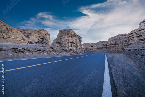 Asphalt road and Yardang landform mountain natural landscape at dusk in Xinjiang. Famous Dahaidao no man's land scenery in China. Outdoor natural background.