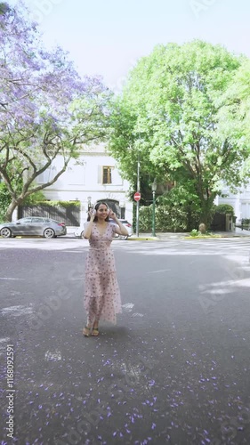 Wallpaper Mural young latin woman walks down the street in springtime while listening to her wireless headphones and walking confidently. Torontodigital.ca