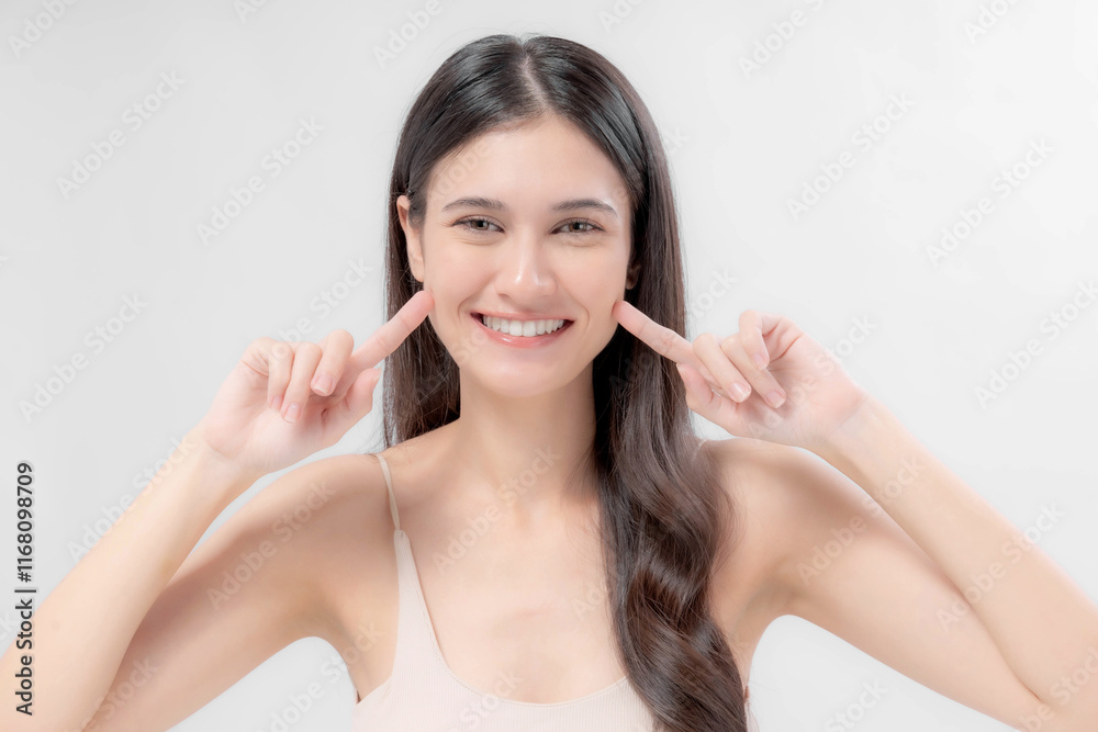 Beautiful Asian woman pointing at her cheeks with both hands while smiling, showing happiness and confidence, isolated on white background, beauty and skincare concept Beautiful Asian woman pointing at her cheeks with both hands while smiling, showing happiness and confidence, isolated on white background, beauty and skincare concept