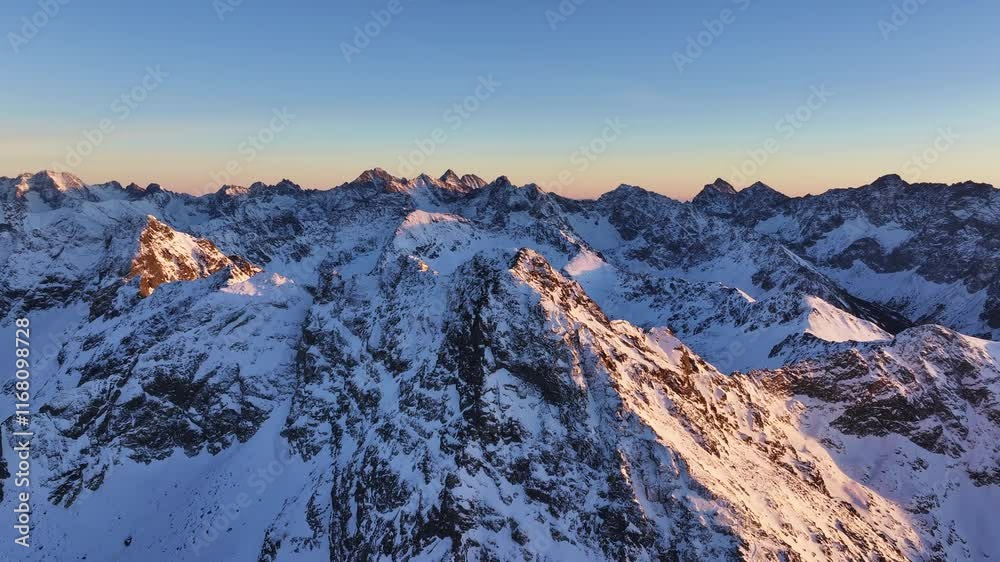 Stunning aerial views of snow-covered mountain peaks at sunrise in the Alps creating a breathtaking winter landscape Stunning aerial views of snow-covered mountain peaks at sunrise in the Alps creating a breathtaking winter landscape