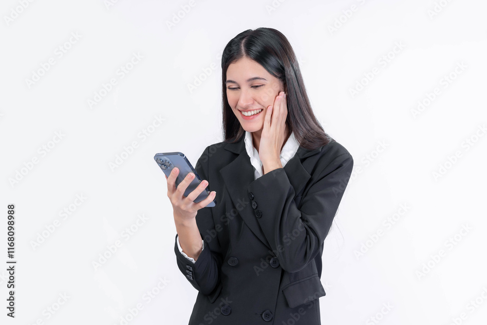 Professional young Asian businesswoman in a formal suit smiling while looking at her smartphone, expressing joy and excitement, standing isolated on a white background Professional young Asian businesswoman in a formal suit smiling while looking at her smartphone, expressing joy and excitement, standing isolated on a white background