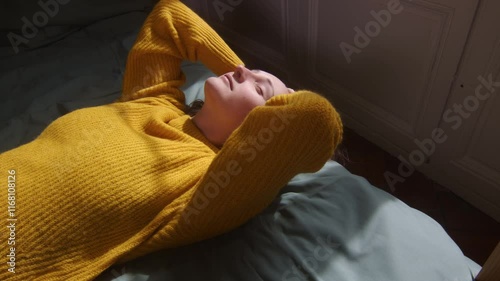 Young woman with a happy face enjoying the sun from the bed