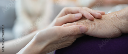 A younger hand tenderly holds an elderly one, symbolizing the loving bond between a mother and child. Mother's day concept. photo