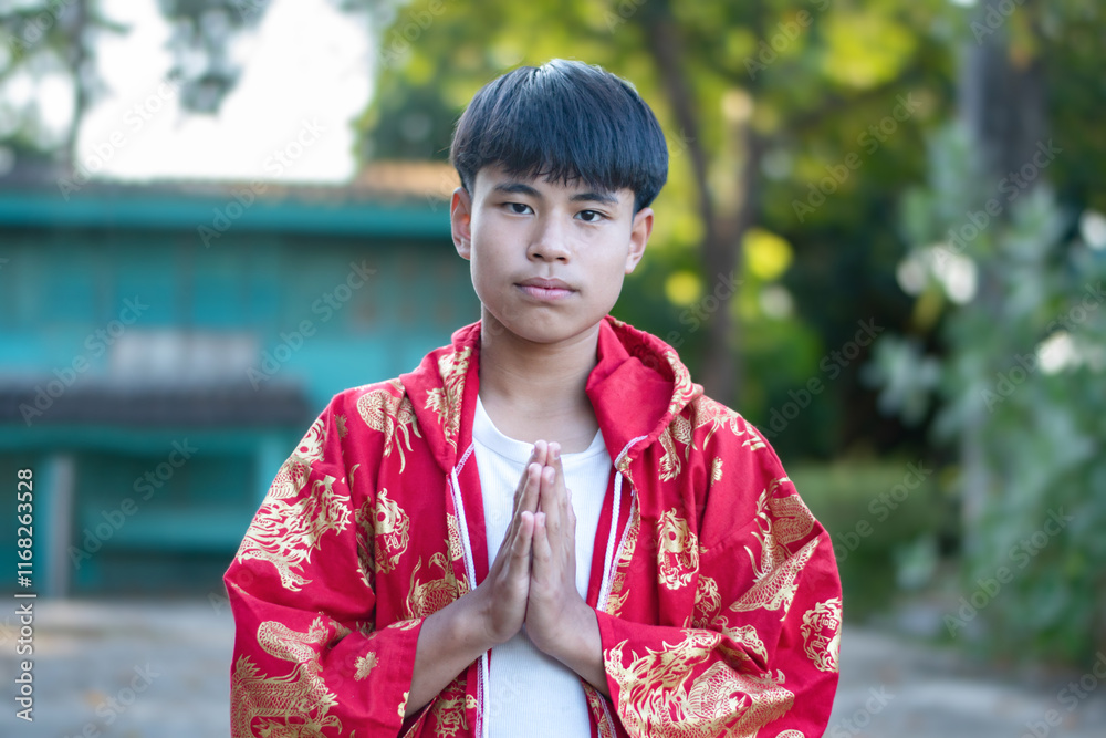 Asian boy in red chinese clothes, showing his respectation with his hands on chest to say thank you for everyone in chinese special occasion. Asian boy in red chinese clothes, showing his respectation with his hands on chest to say thank you for everyone in chinese special occasion.