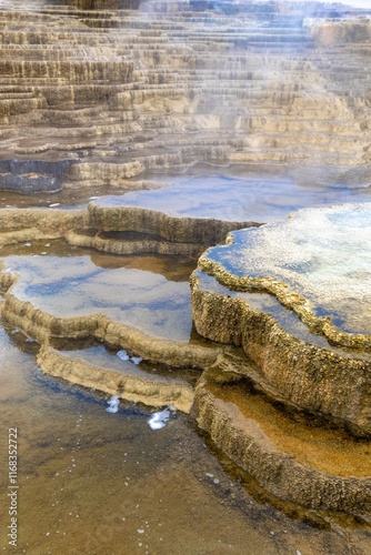 Layered hot spring terraces, mineral deposits, natural pools. Steam rises from the pools. Geological wonder. Mammoth Hot Springs, Yellowstone National Park, Wyoming, USA. photo