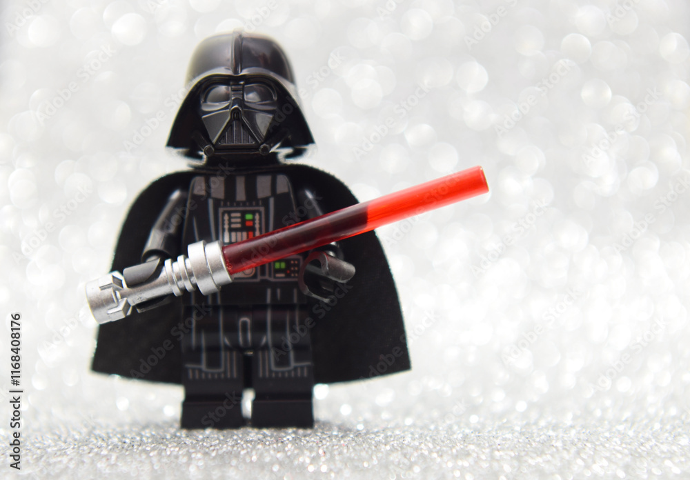 Naklejka premium Lego minifigure of Darth Vader from Star Wars with lightning sword isolated on black. Editorial illustrative image of popular plastic constructor.