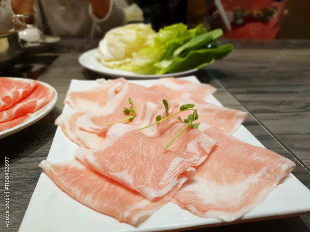 Delicious hot pot eating at a restaurant, Chinese and Japanese hot soup beef meat and pork sliced in plate, cabbage vegetable in white bowl, traditional food stock photo Delicious hot pot eating at a restaurant, Chinese and Japanese hot soup beef meat and pork sliced in plate, cabbage vegetable in white bowl, traditional food stock photo