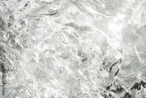 Abstract grayscale image of water surface texture with light reflections and ripples.