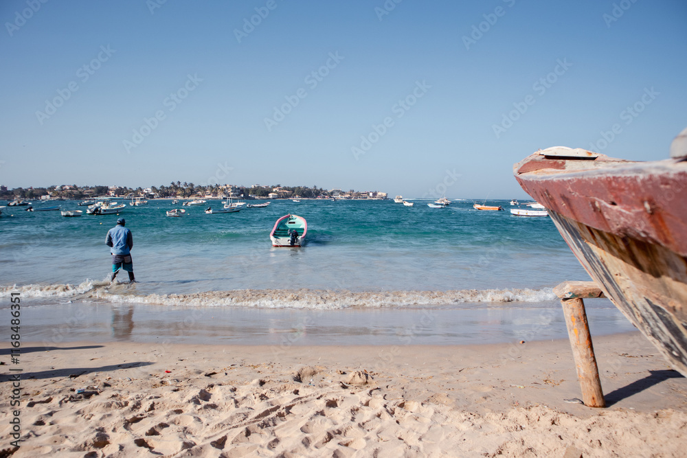 Typical fishing boats in Yoff Dakar, Senegal, called pirogue or piragua or piraga. Colorful boats used by fishermen standing on the beach..