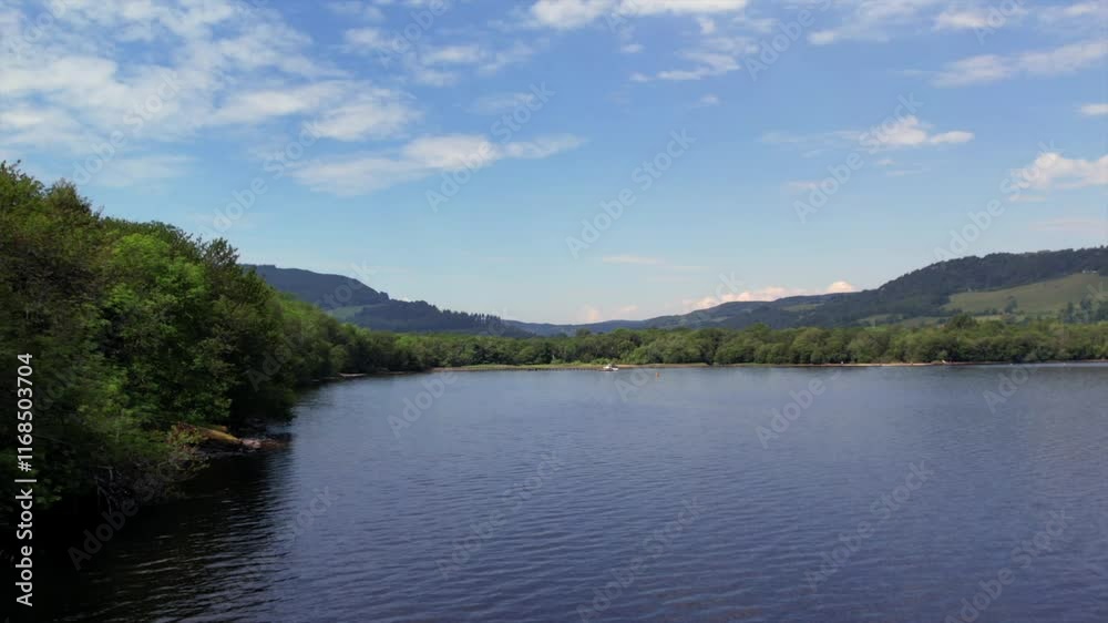 Loch Ness shoreline with lush green forests and calm water reflecting the vibrant blue sky. Captures the picturesque scenery and iconic landscape of the Scottish Highlands. Loch Ness shoreline with lush green forests and calm water reflecting the vibrant blue sky. Captures the picturesque scenery and iconic landscape of the Scottish Highlands.