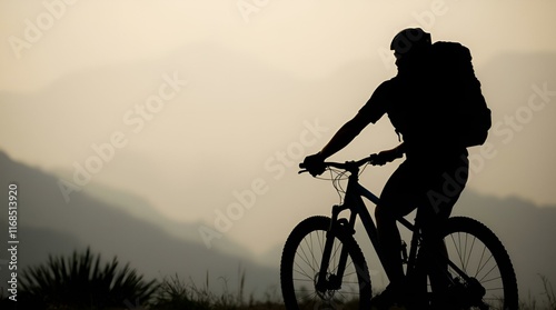 Cyclist silhouette adventurously riding against mountain sunset photo