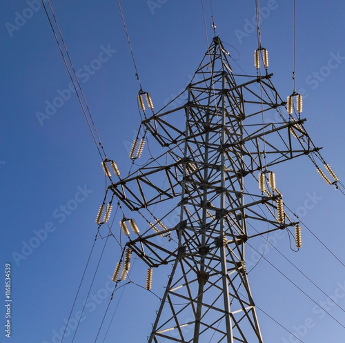 support for a high-voltage power line against the blue sky and sunlight. close up photo