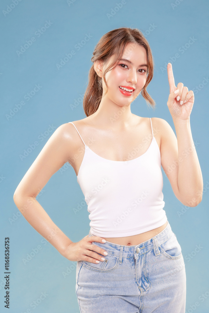 Fototapeta premium Young Asian beauty happy woman pull back hair with Koreans makeup style on face and perfect clean skin show point finger on isolated blue background.
