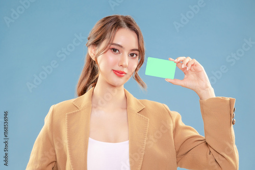 Young attractive elegance Asian woman hand showing mock up credit card with happy relax carefree face expression portrait look at camera on blue background instudio. photo