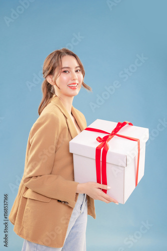 Young attractive elegance Asian woman hand showing mock up gift box with happy relax carefree face expression portrait look at camera on blue background instudio. photo